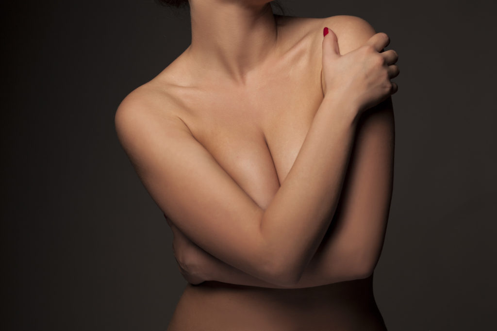 female torso with hands covering breasts