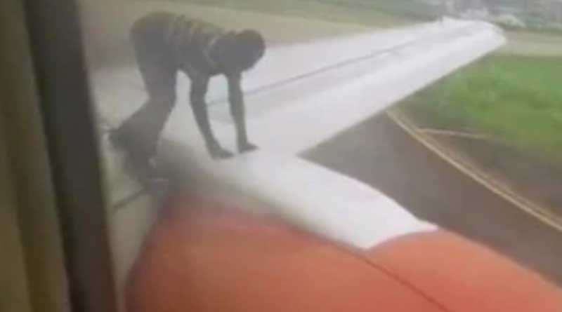 Nigerian man climbs on aircraft wings as plane readies for takeoff.