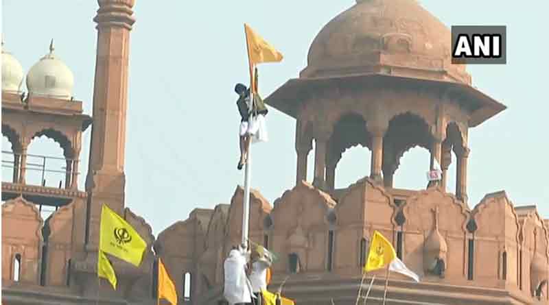 A protestor hoists flag from the ramparts of the Red Fort | Sangbad Pratidin