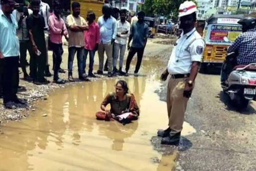 A woman in Hyderabad sat in a pothole filled with muddy water